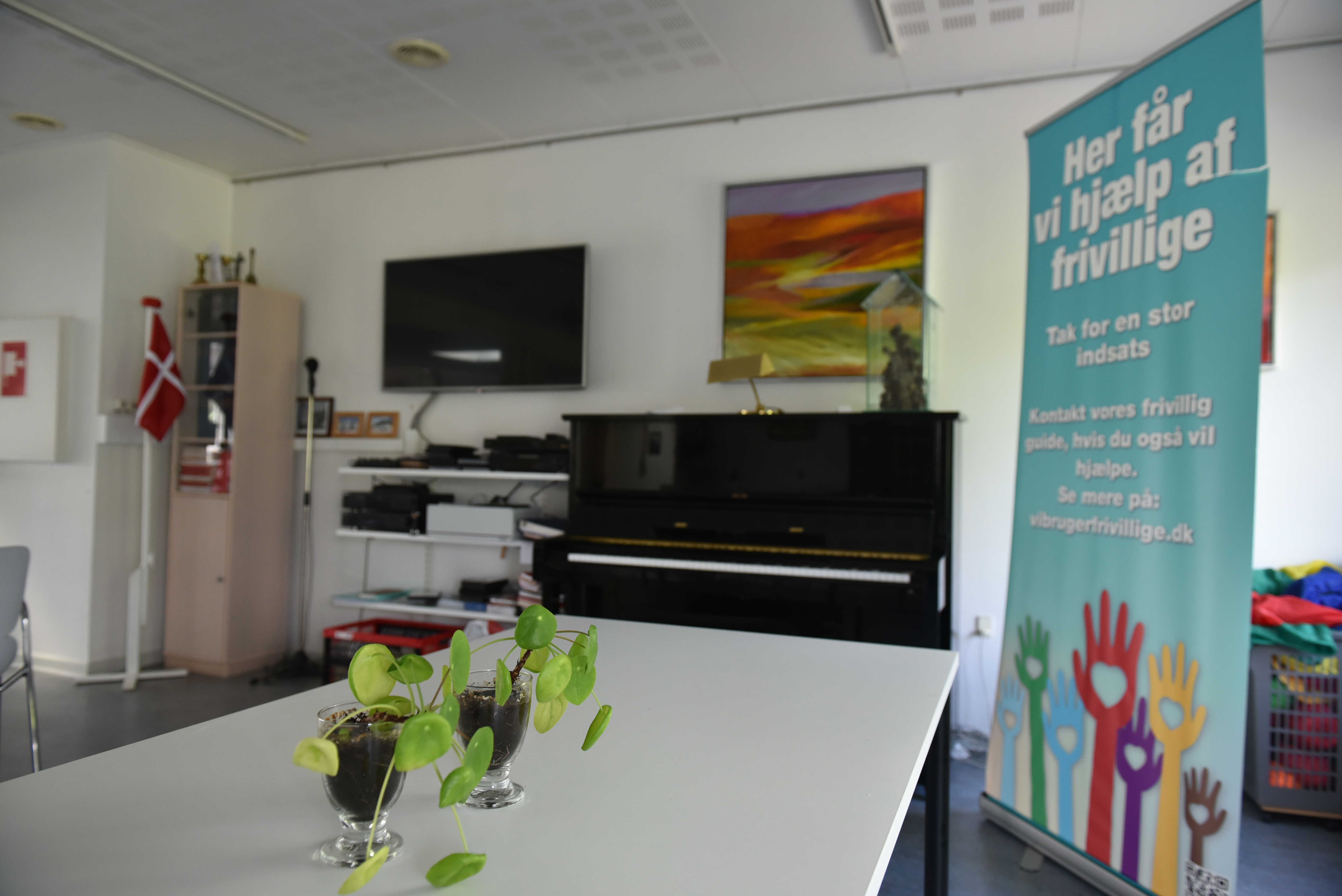 Opholdsrum med spisepladser og klaver hos Spentrup Ældrecenter